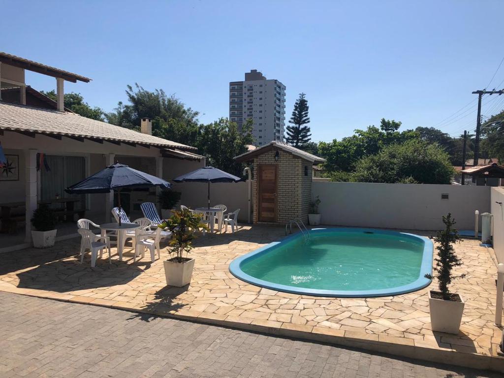 una piscina con sillas, una mesa y sombrillas en Mundo Livre Guest House, en Penha