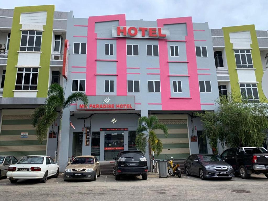 a pink hotel with cars parked in a parking lot at MK Paradise hotel in Tangkak
