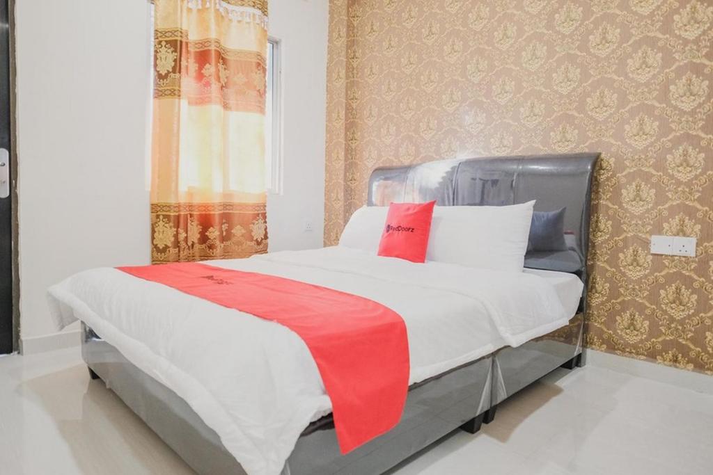 a bedroom with a bed with a red blanket on it at RedDoorz Apartment @ Batam Centre 3 in Batam Center