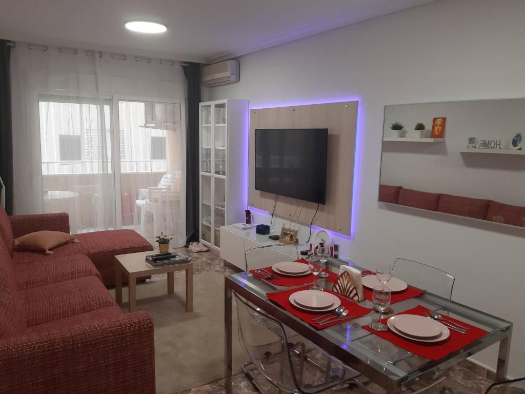 ein Wohnzimmer mit einem Tisch und einem TV in der Unterkunft Modern Apartment On Playa Del Cura in Torrevieja