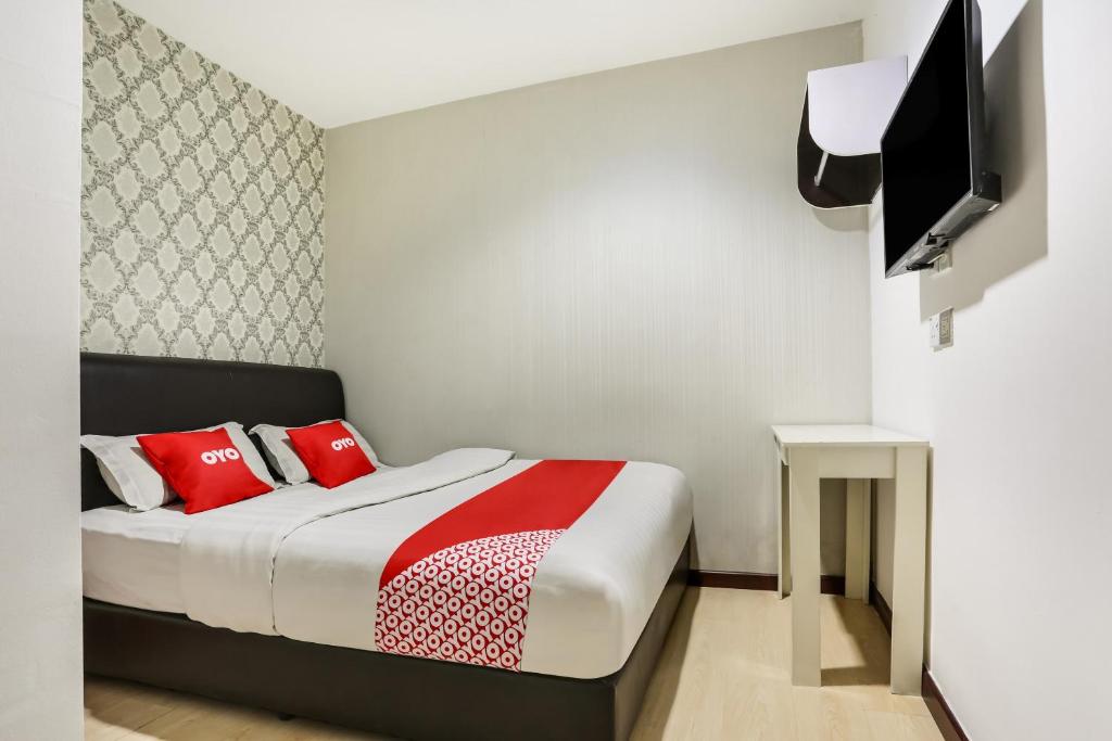 een slaapkamer met een bed met rode kussens en een televisie bij OYO 89583 Grove Hotel in Kajang