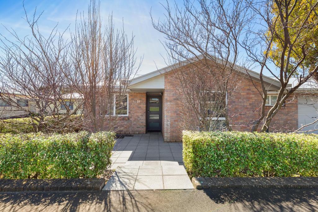 a brick house with a door and some bushes at City One Apartment in Mount Gambier