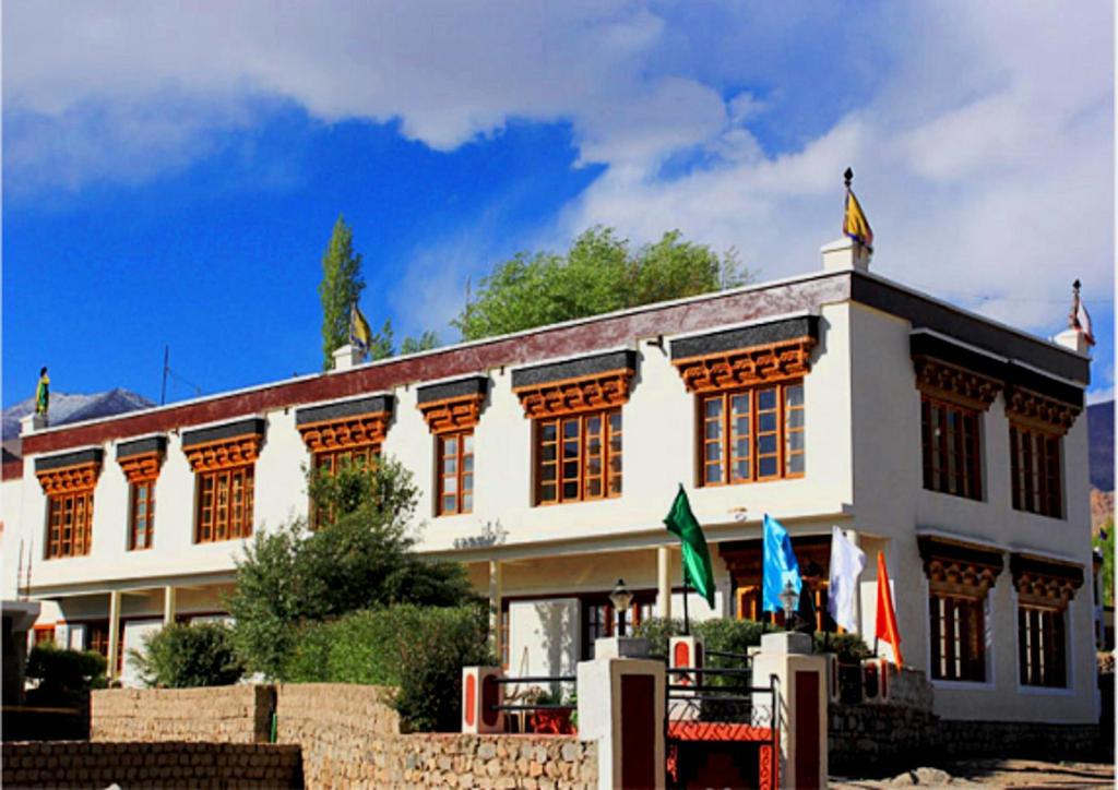 a large white building with flags in front of it at Hotel Mahay Palace in Leh