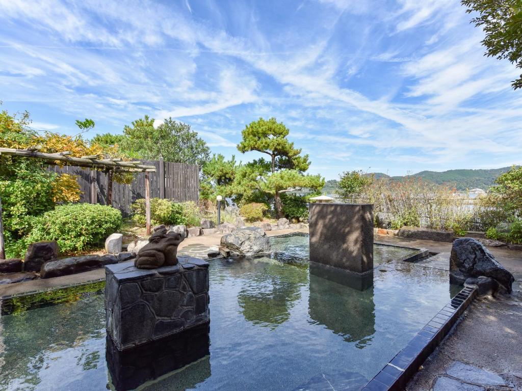 una piscina de agua en un jardín con rocas y árboles en Yozyokan, en Yurihama