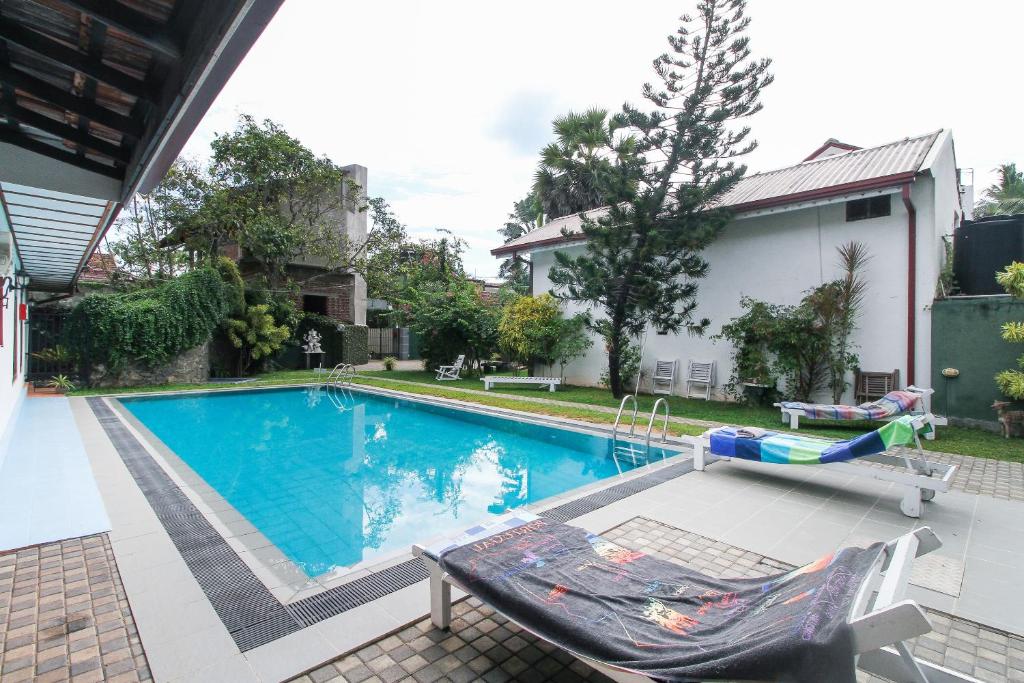 een zwembad in een tuin met een stoel bij Lioni Holidays Villa in Negombo