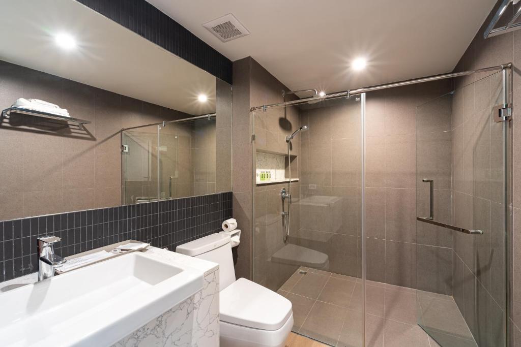 A tiled bathroom with a glass-enclosed shower, toilet and vanity sink.