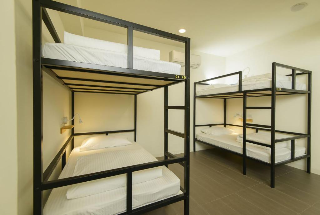 嘉義市にある客旅家青年旅館 Travelers Plusの二段ベッド3組(白いシーツ付)が備わる客室です。