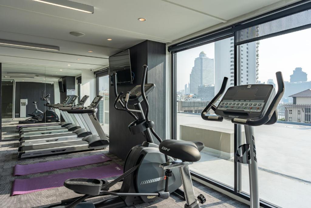 A bright hotel gym with treadmills, cardio machines and a city view.