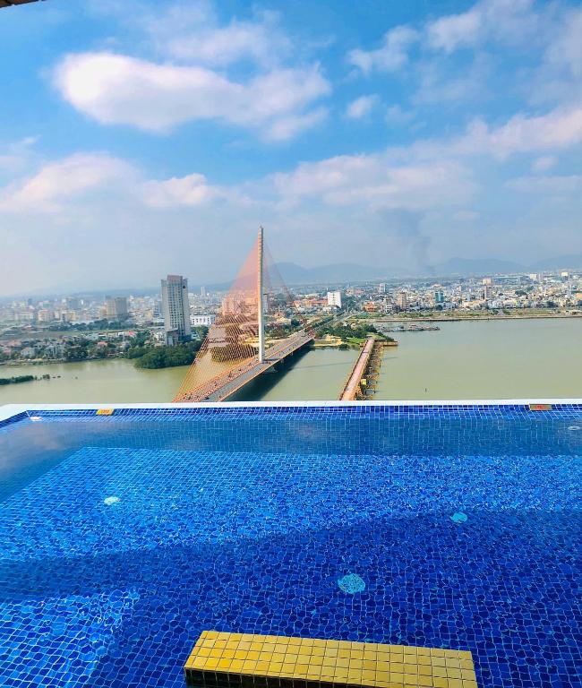 An infinity pool looks across a river toward a cable-stayed bridge and Da Nang skyline.