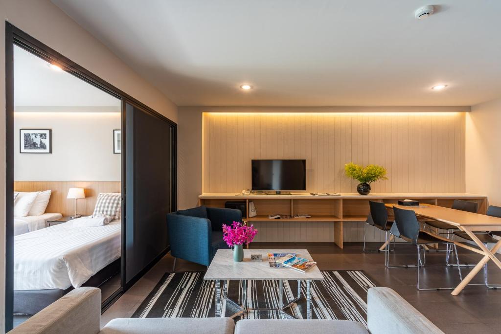 A spacious living area with a television, dining table and a separate bedroom beyond sliding doors.