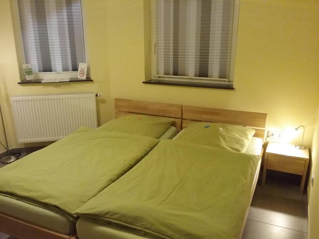 a bed with green sheets and pillows in a bedroom at Pension Wauri , Gästezimmer in Waldenbuch