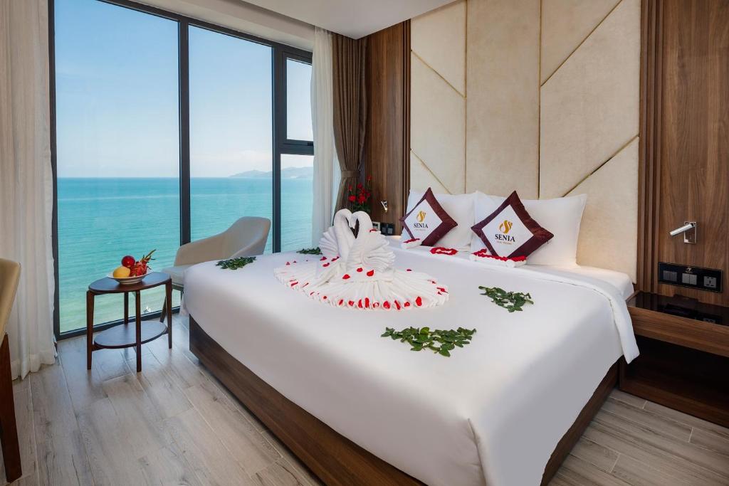 a bedroom with a large white bed with a large window at Senia Hotel Nha Trang in Nha Trang