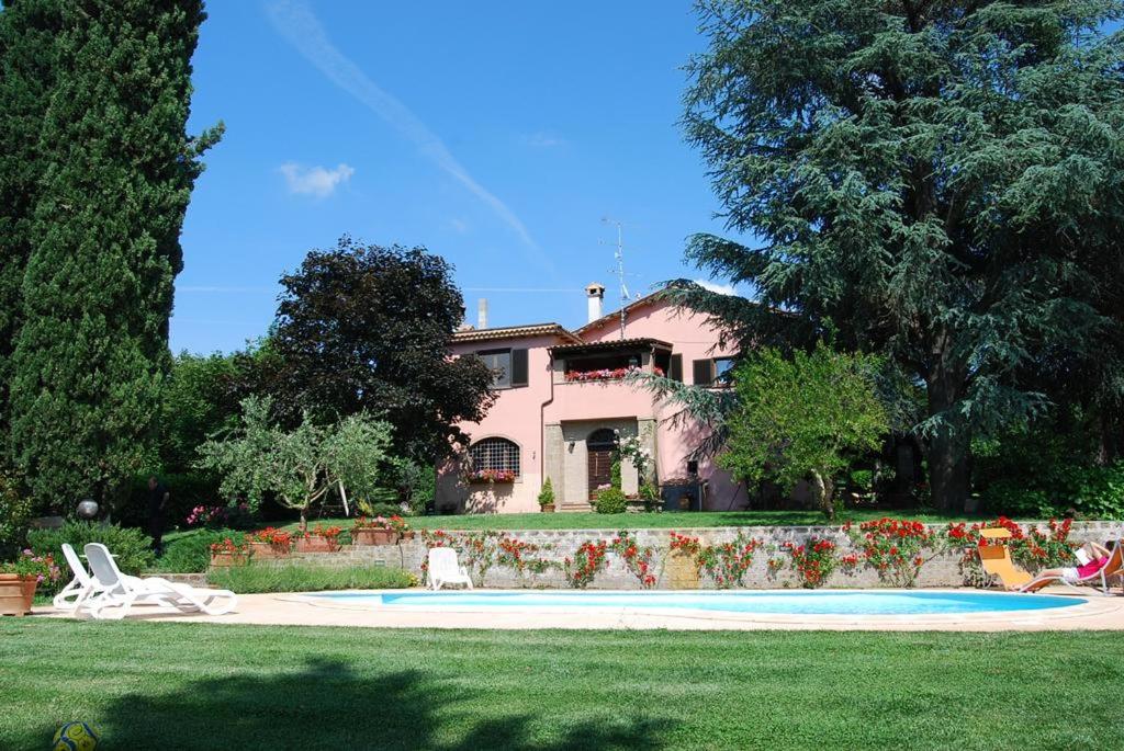 a pink house with a yard with a swimming pool at Ai due Cedri in Capranica