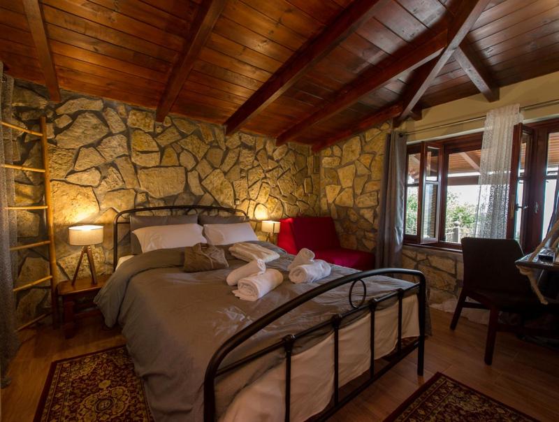 a bedroom with a bed and a stone wall at Petra Thea Villa Karitaina in Karítaina