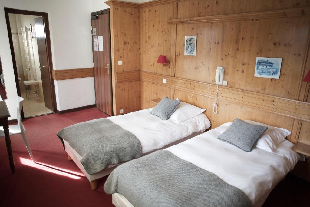 two beds in a room with wood paneling at Hôtel Val d'Este in Saint-Gervais-les-Bains
