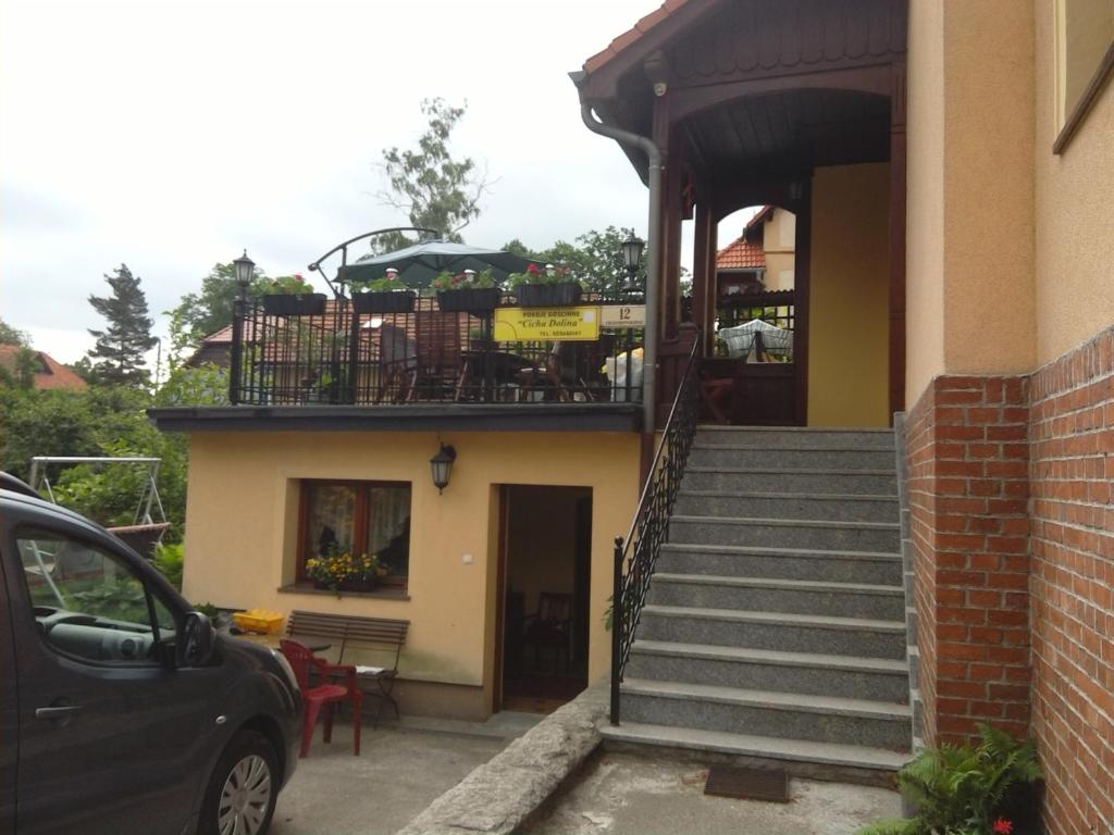 een huis met een trap en een balkon met een auto bij Pokoje gościnne Sobieszow in Jelenia Góra