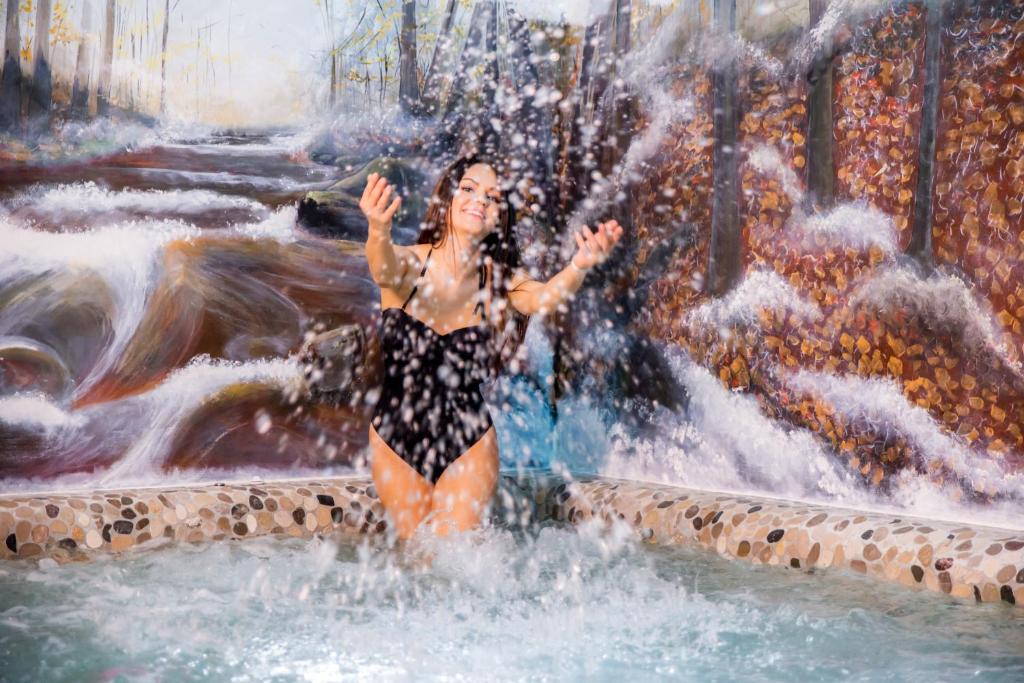 une femme debout dans une fontaine dans une cascade dans l'établissement Dolomiti Village, à Comeglians