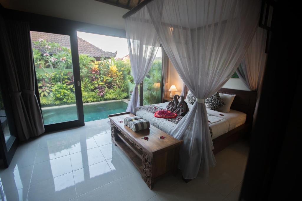 a bedroom with a canopy bed and a pool at Rumah mini in Ubud