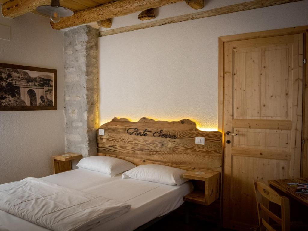 a bedroom with a bed with a wooden headboard at Locanda Ponte Serra in Lamon