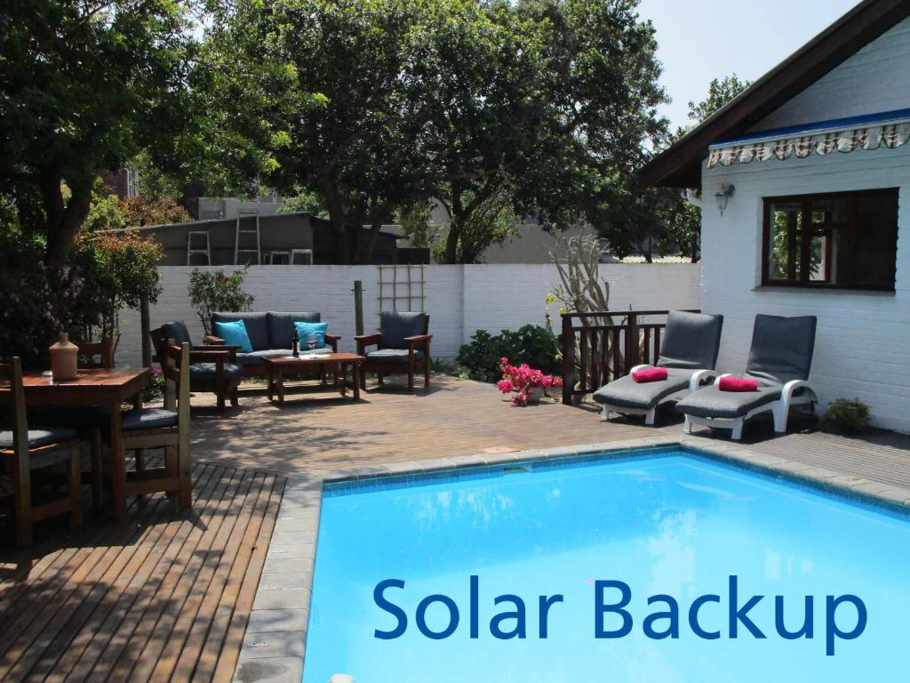 a swimming pool with chairs and a table and chairs at Inn2Wilderness Guesthouse in Wilderness