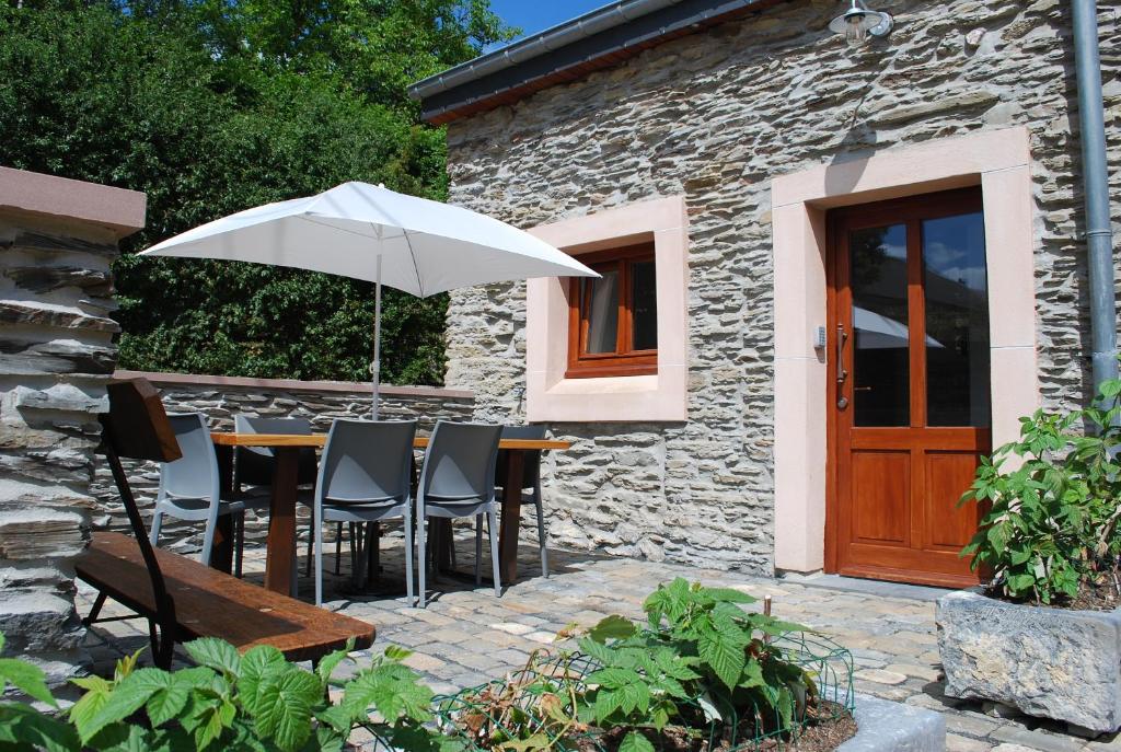 une table et des chaises avec un parasol en face d'un bâtiment dans l'établissement Gîte Bed & Bedot, à Fauvillers