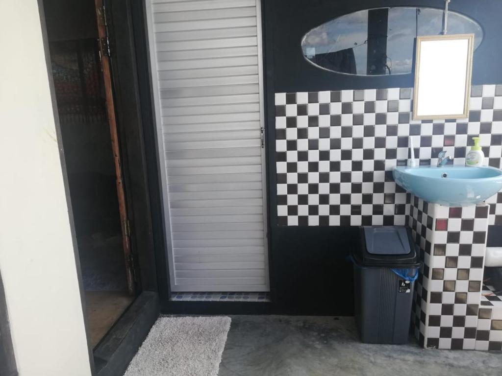 a bathroom with a sink and a checkered wall at Smiley's Homestay in Berastagi