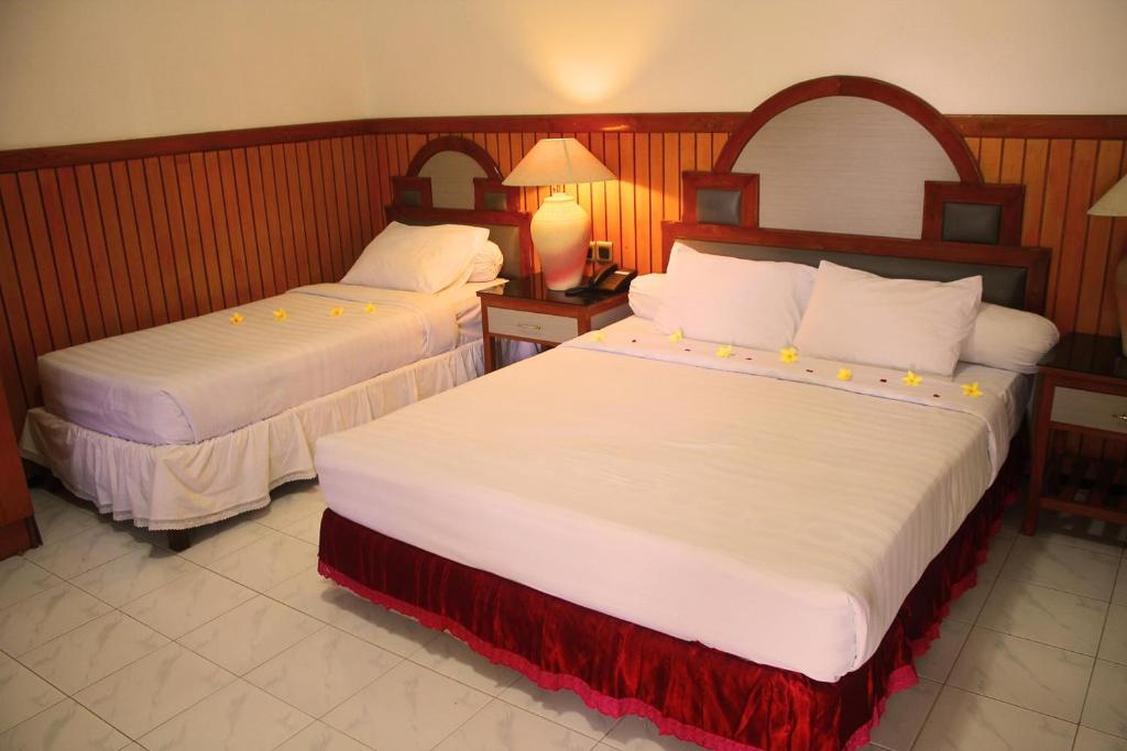 a hotel room with two beds with white sheets at Berlian Abadi Hotel by Sinergi in Banyuwangi