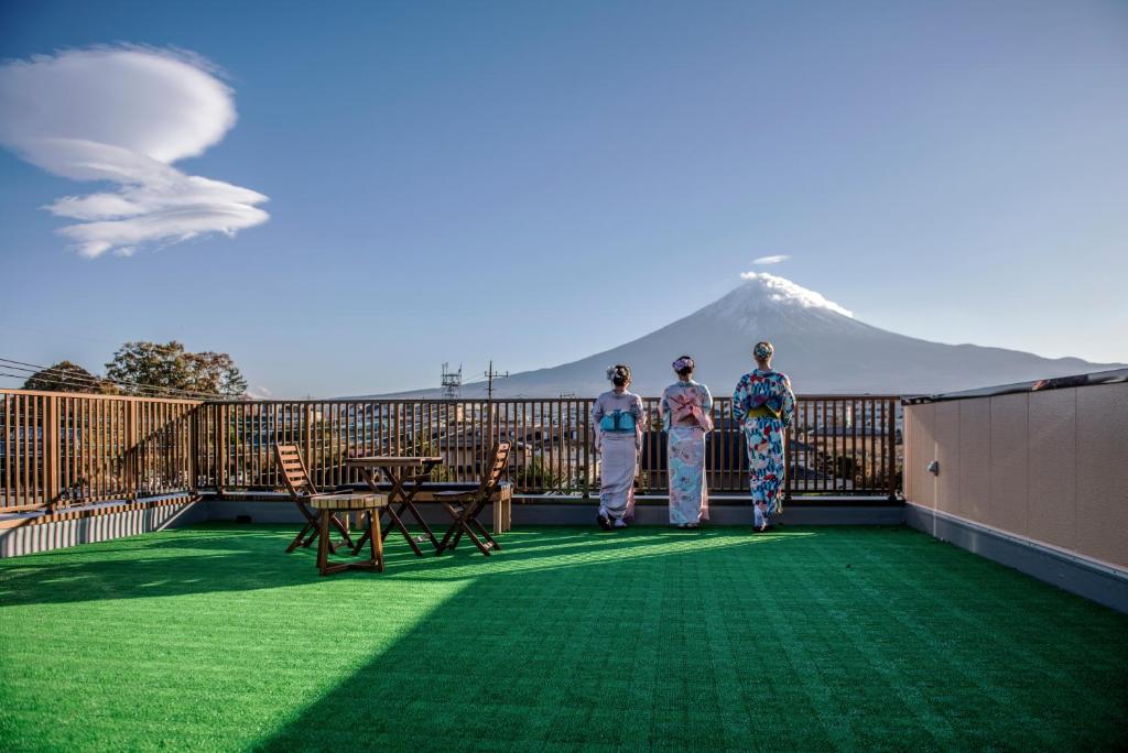 Tres personas de pie en un balcón con una montaña en el fondo en HAOSTAY, en Fujikawaguchiko