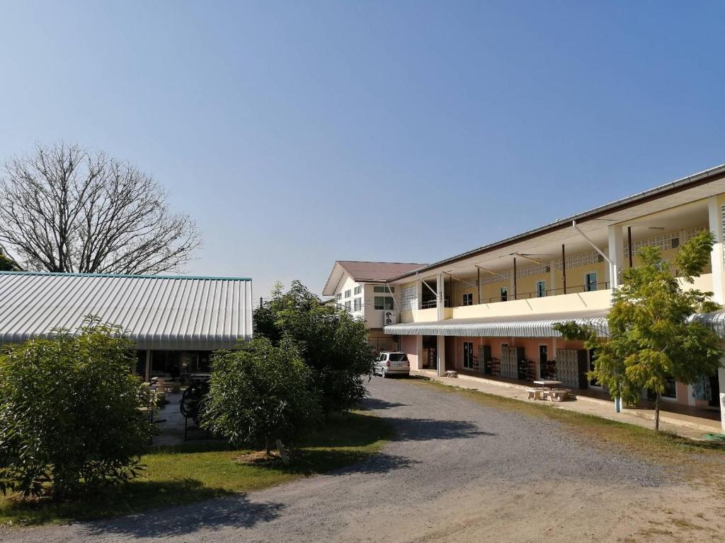 a building with a parking lot in front of it at Armthong Resort in Nakhon Nayok