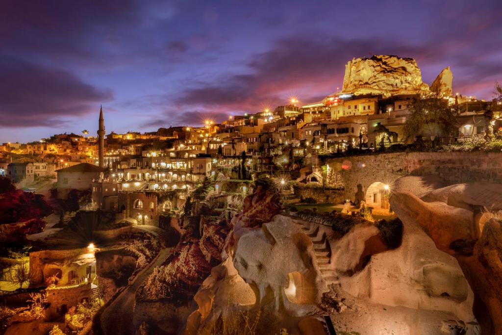 una ciudad iluminada por la noche con edificios en Argos in Cappadocia, en Uchisar