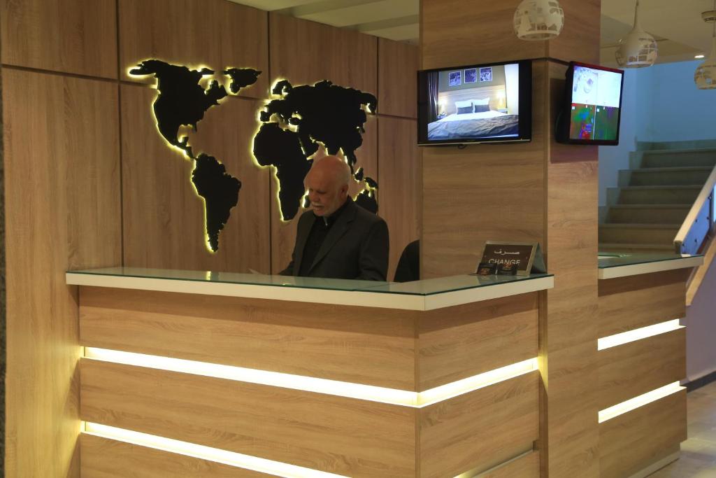 un hombre sentado en un escritorio con un mapa del mundo en una pared en MONDIAL HOTEL, en Túnez