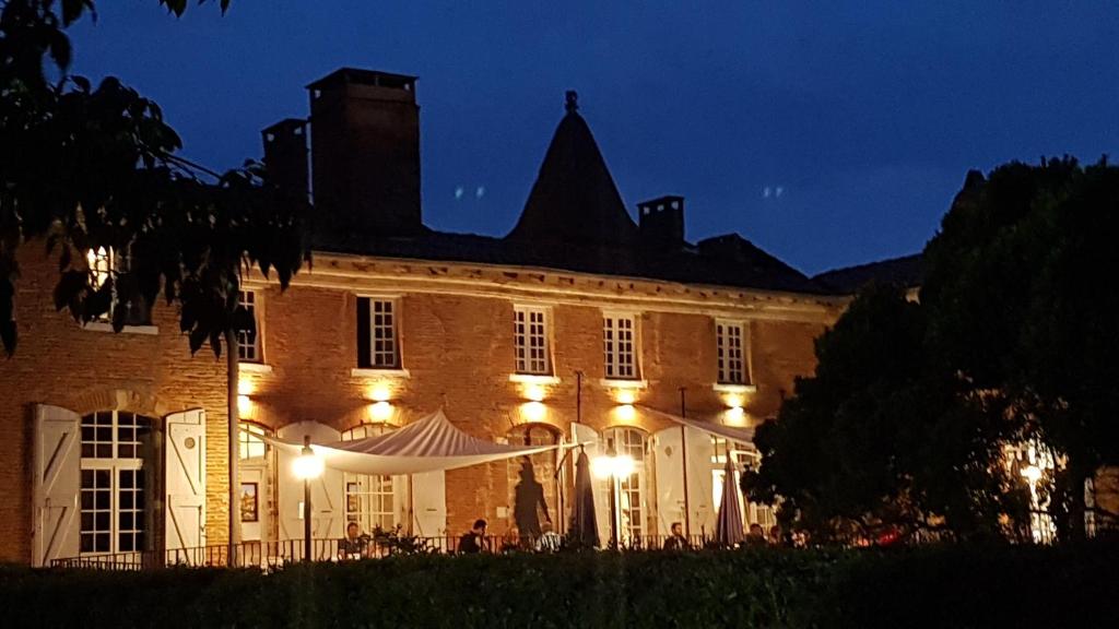 een groot gebouw met 's nachts verlichting bij Logis Domaine de Peyrolade in Daux