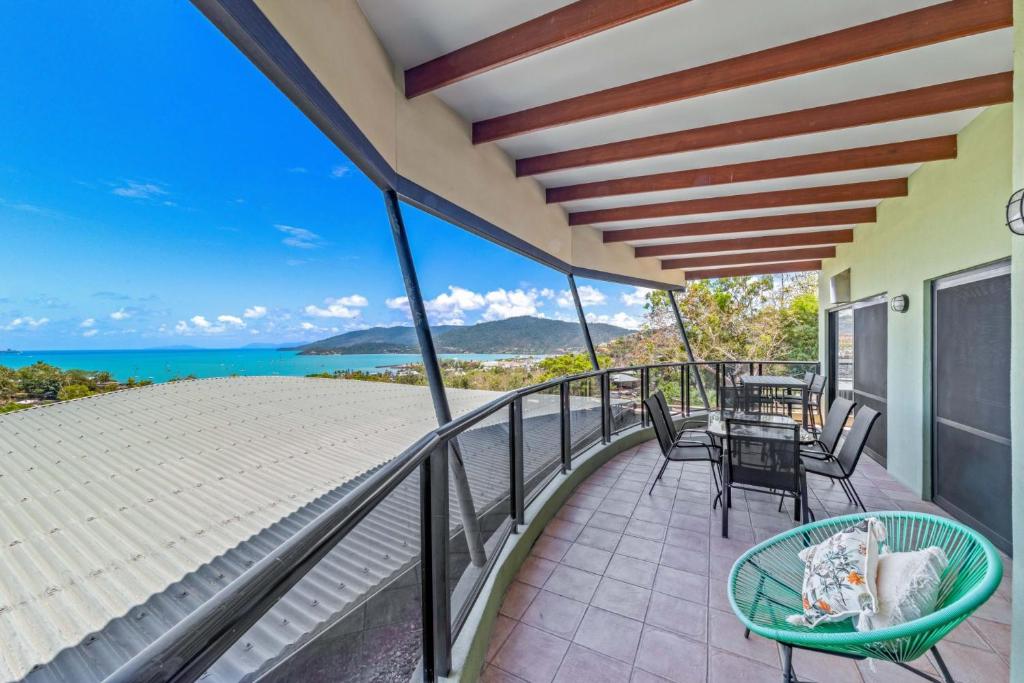 a balcony with a table and chairs and the ocean at Ambience of Airlie - Airlie Beach in Airlie Beach