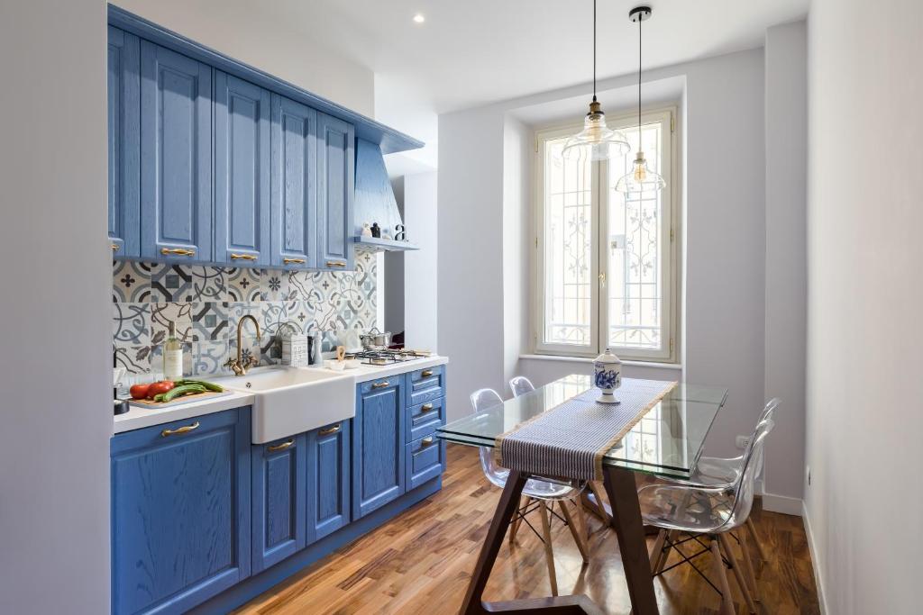 a kitchen with blue cabinets and a glass table at Celestina House in Rome