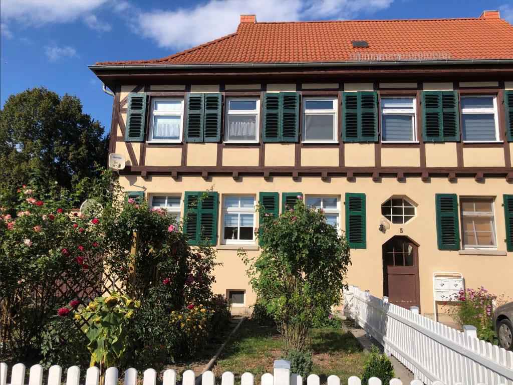 a house with green shutters and a white fence at Ferienwohnung Rosenblick in Bad Langensalza