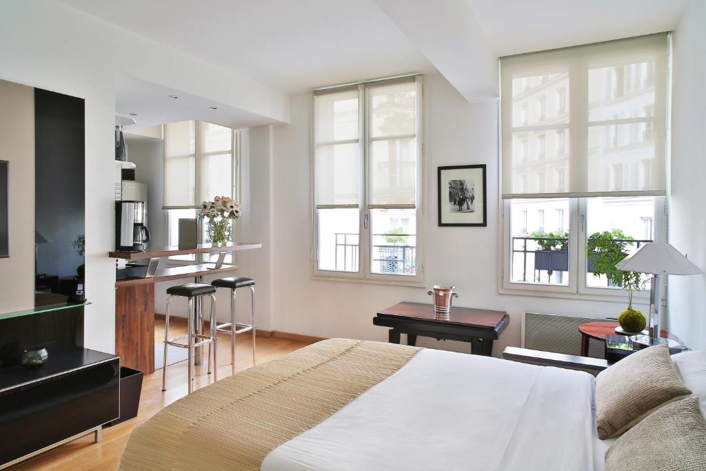 a bedroom with a bed and a kitchen with windows at Montmartre Residence in Paris