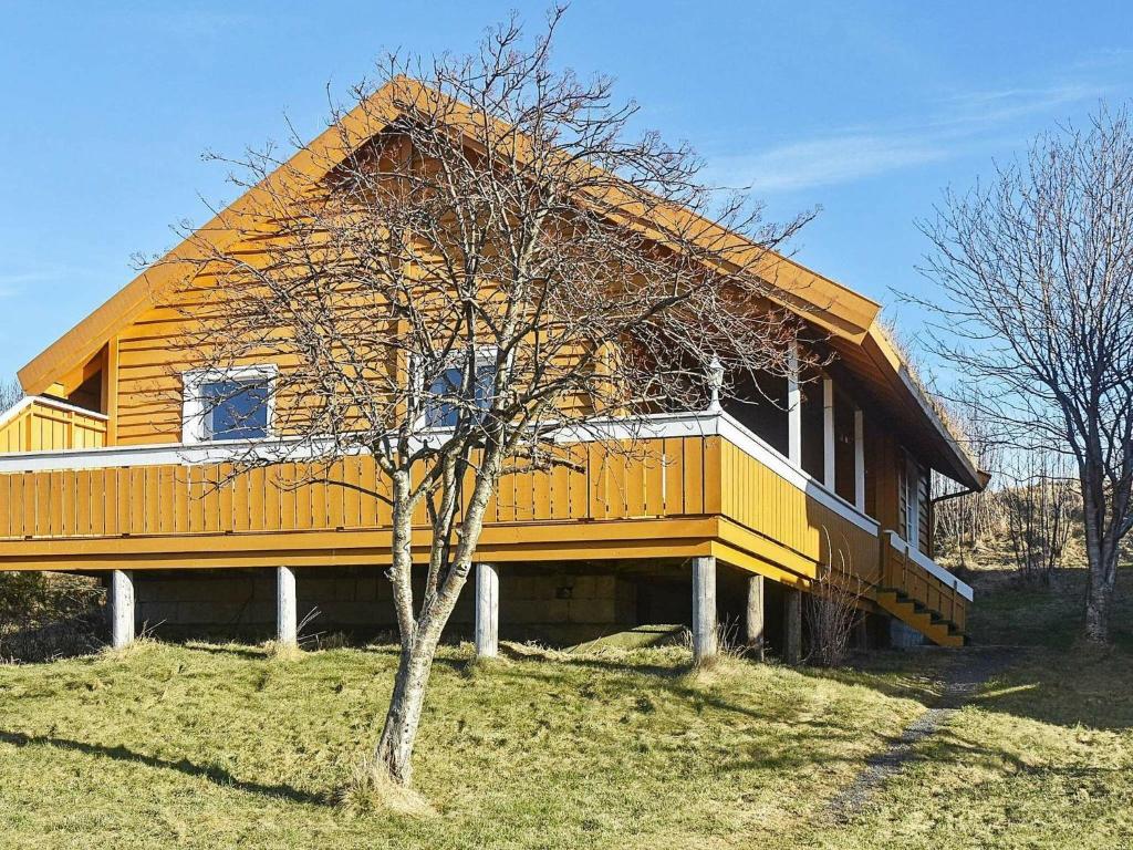 Una casa amarilla con un árbol delante. en Holiday home Aukra III, en Aukra