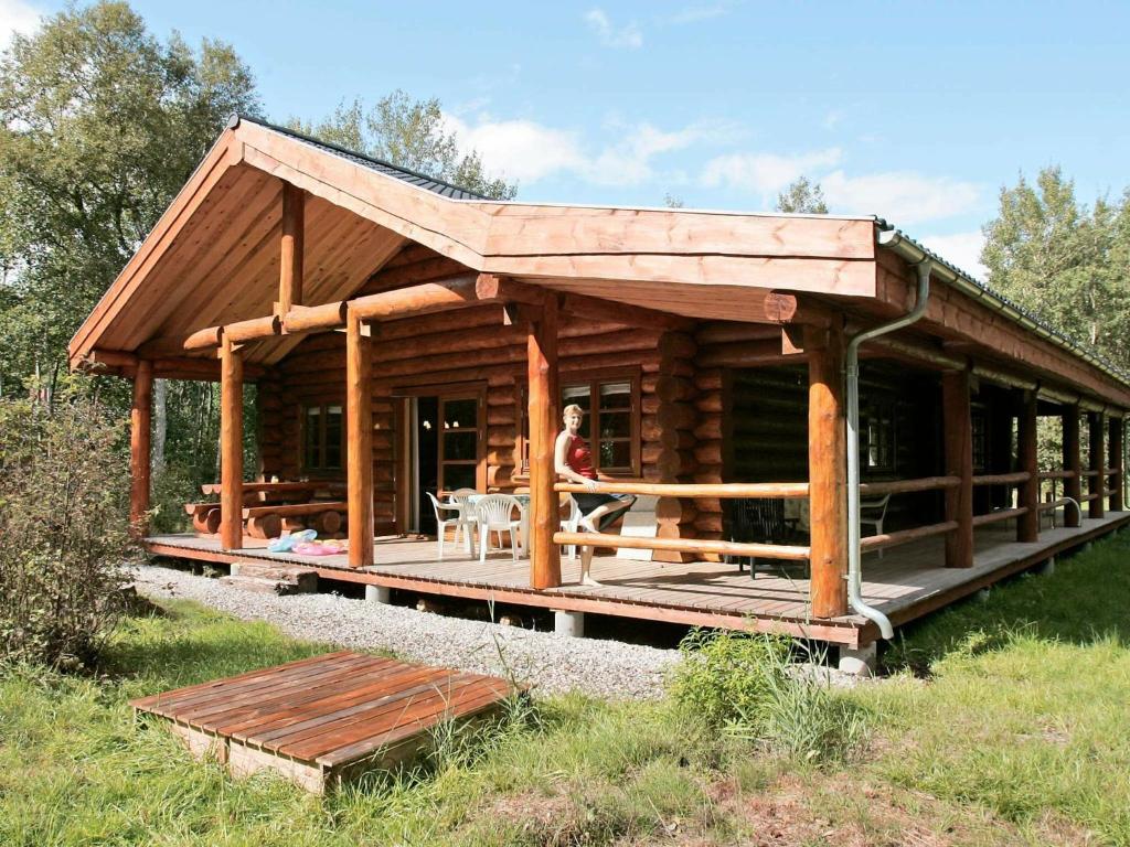 uma cabana de madeira com uma pessoa sentada num alpendre em 10 person holiday home in Hadsund em Odde