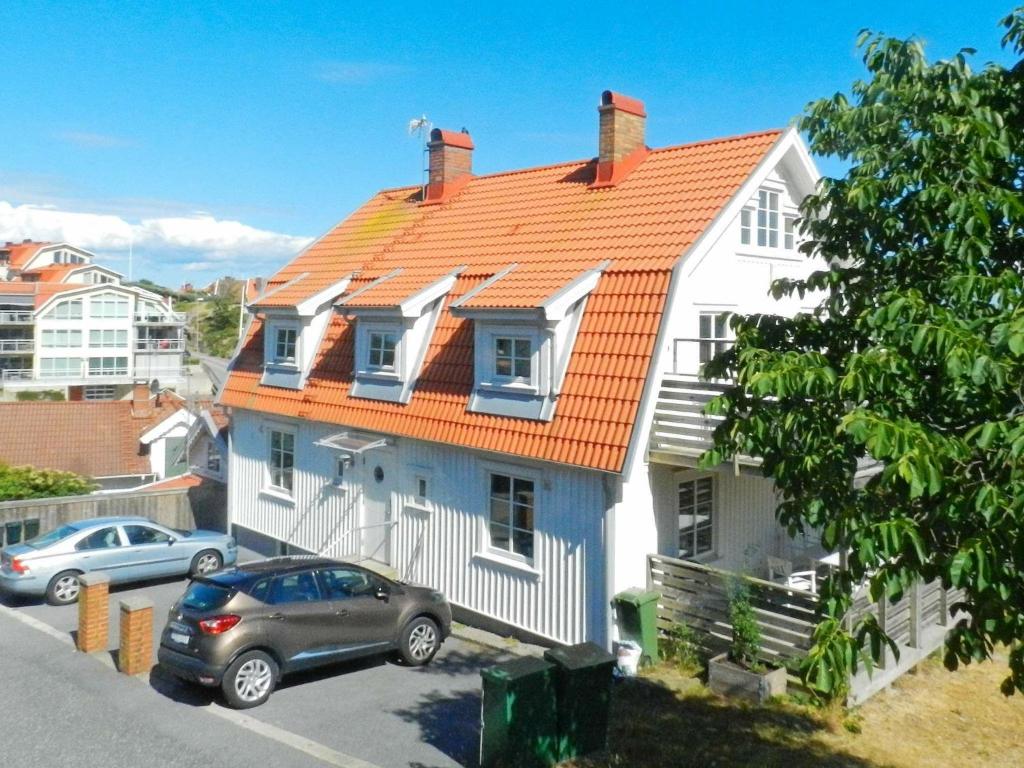 dom z pomarańczowym dachem i samochodami zaparkowanymi przed budynkiem w obiekcie 5 person holiday home in LYSEKIL w mieście Lysekil