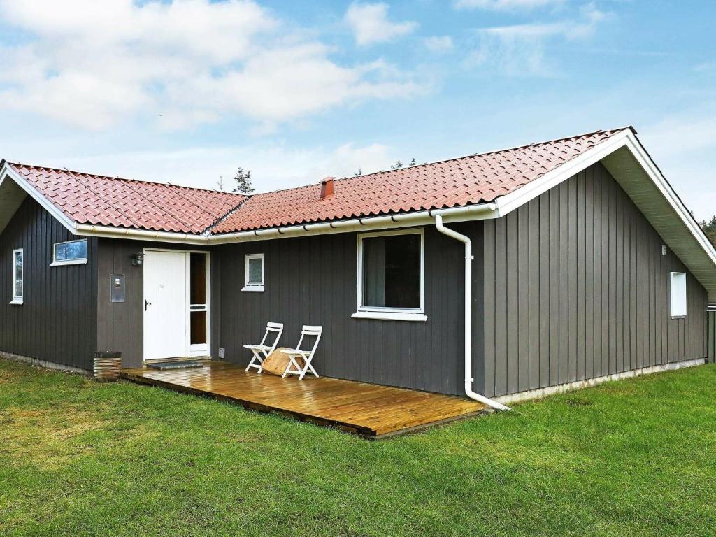 ein Haus mit einer Terrasse und zwei Stühlen darauf in der Unterkunft Holiday home Løkken X in Løkken