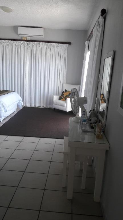 a room with a bed and a table and a room with a bed sqor at Casa Do Mar Guest House in Praia do Tofo