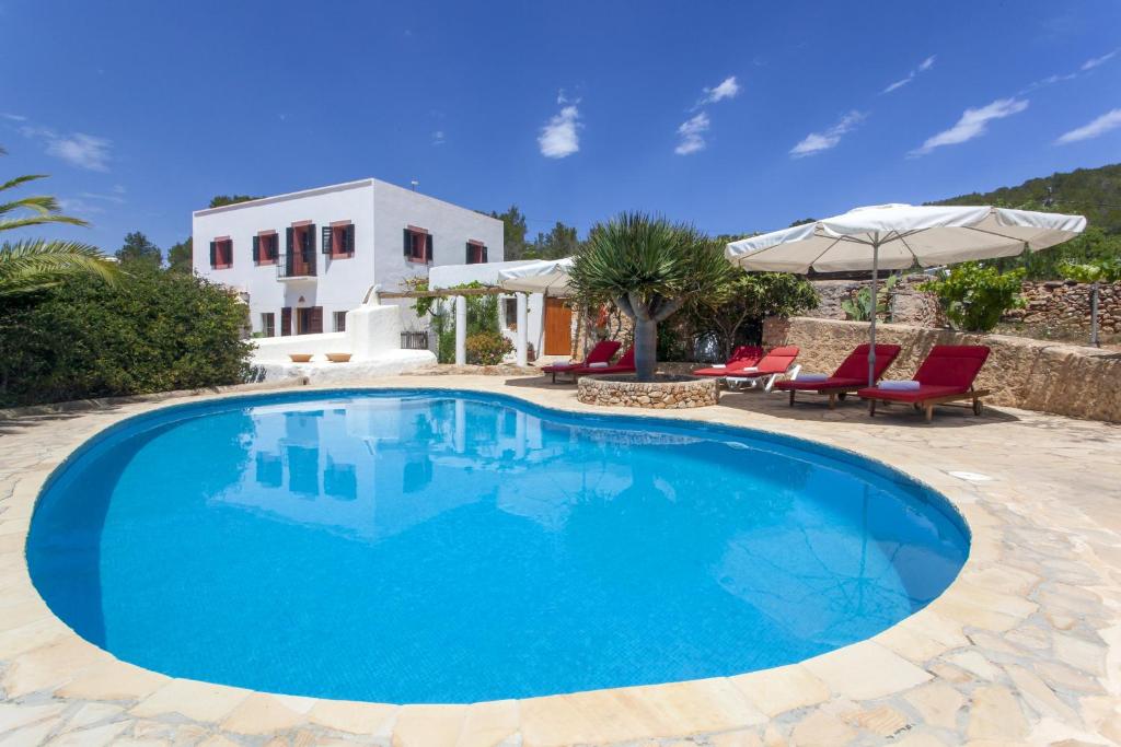 une grande piscine bleue en face d'une maison dans l'établissement Pau de Baix, à Sant Antoni de Portmany