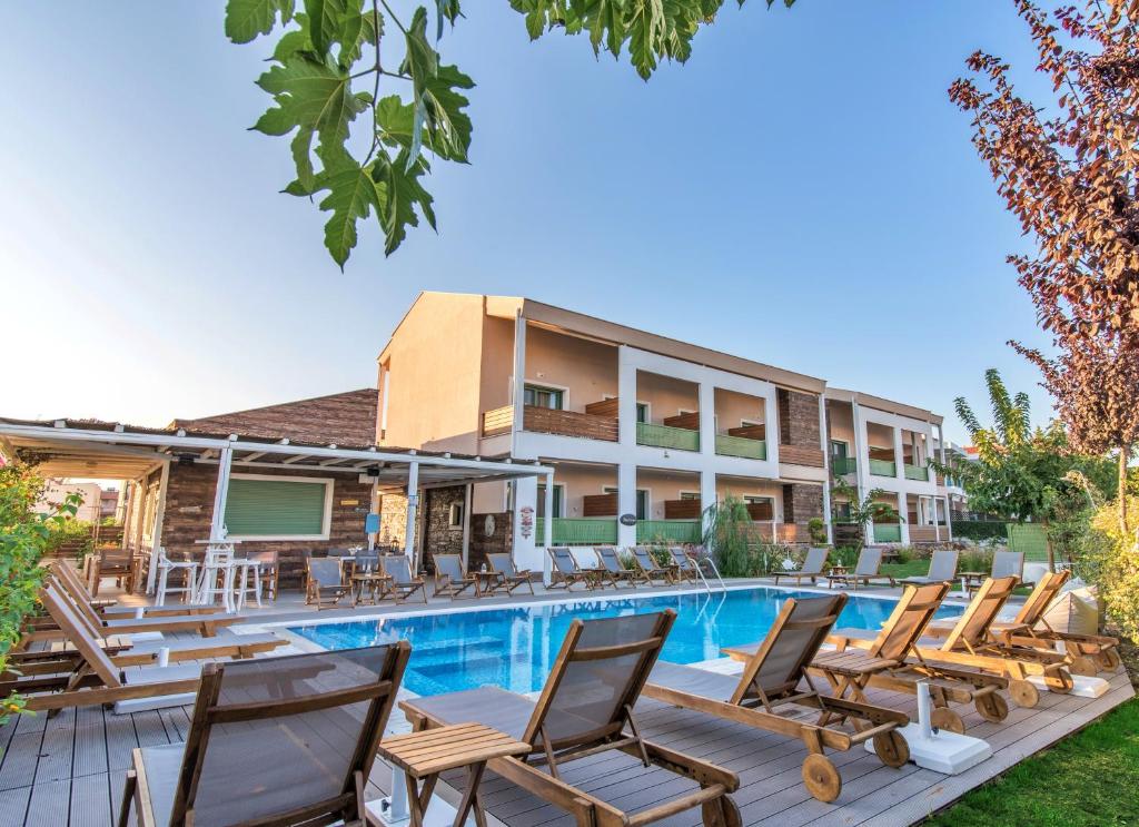 a hotel with a swimming pool and lounge chairs at Alegria Suites in Nikiti