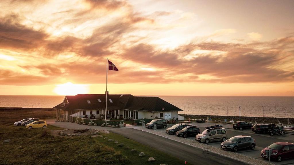 a building with cars parked in a parking lot near the ocean at Hanstholm Madbar in Hanstholm