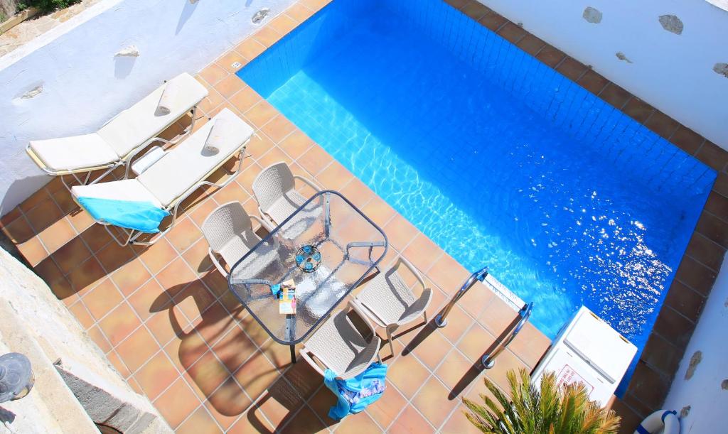 Sívas的住宿－Villa Radamanthis，享有带椅子和桌子的游泳池的上方景色