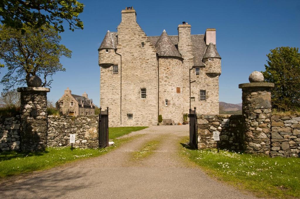 um velho castelo com uma cerca de pedra e uma estrada em Barcaldine Castle em Oban