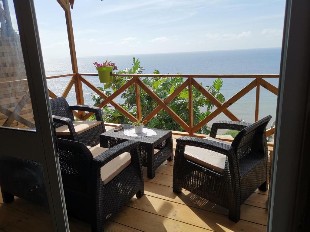 a balcony with a table and chairs and the ocean at La maison du nord, T2 privé in Mtsangadoua