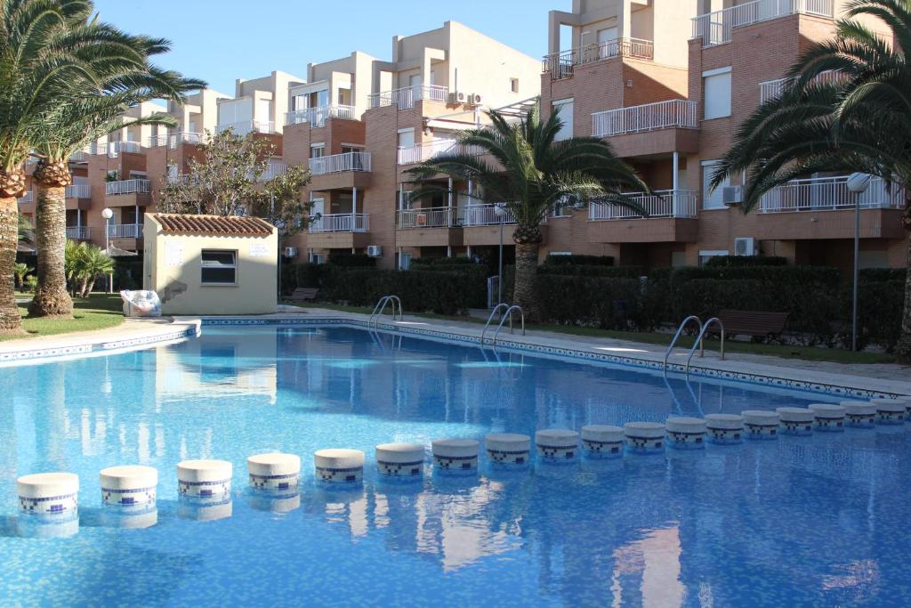 una gran piscina con palmeras y edificios en 192 Mediterráneo Playa, en Denia