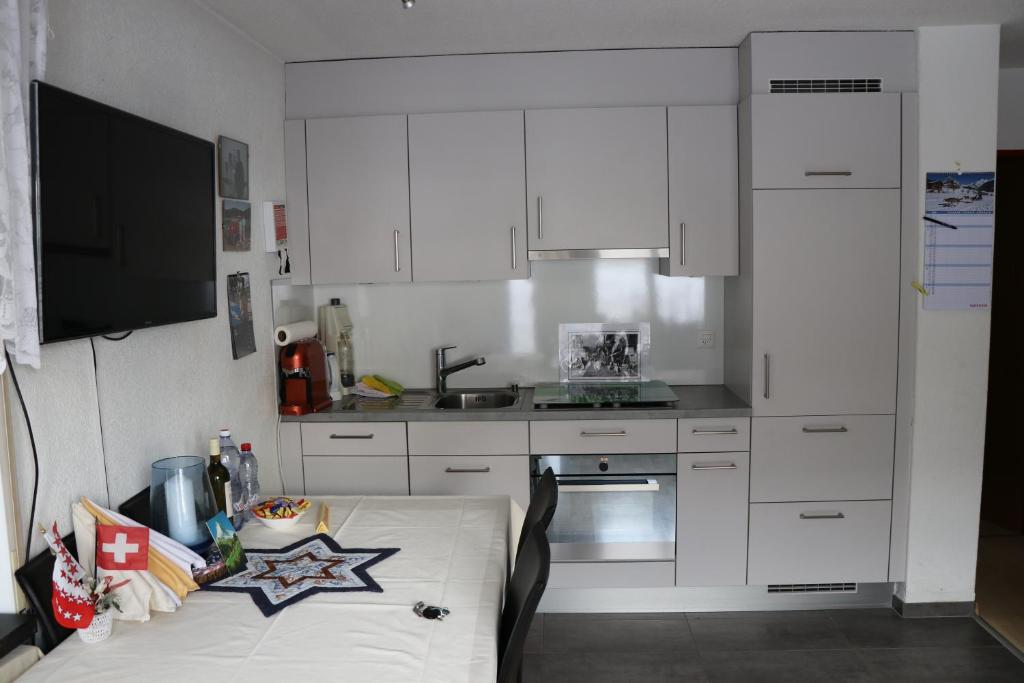 a kitchen with white cabinets and a table in it at Bodmen 3 Apartments von Privat in Zermatt in Zermatt