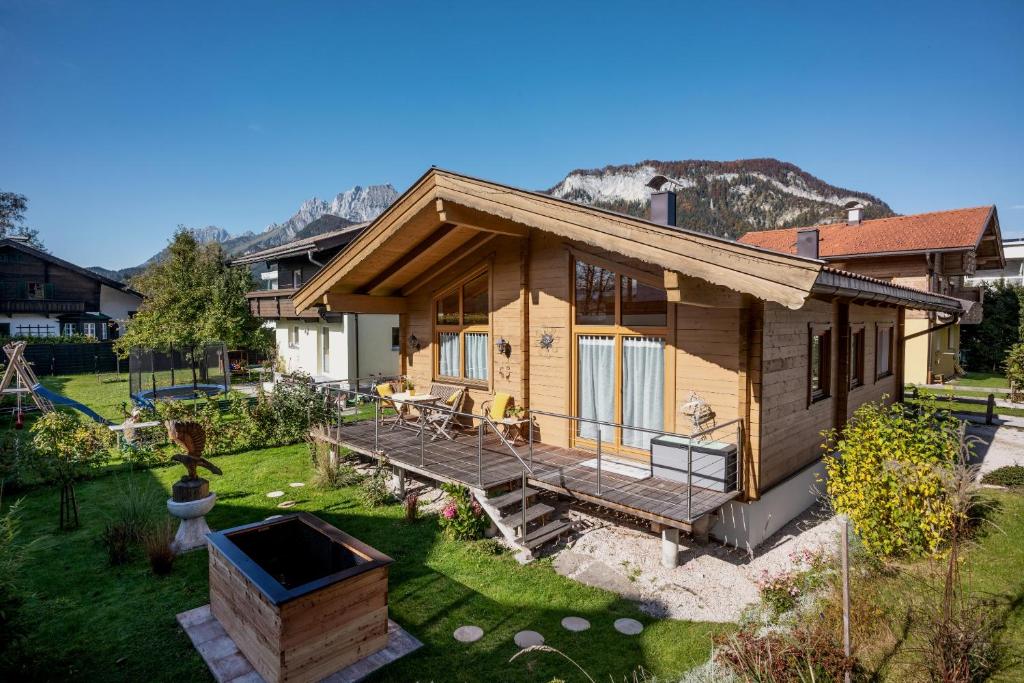 a wooden house with a deck and a yard at Chalet Terry in Sankt Johann in Tirol